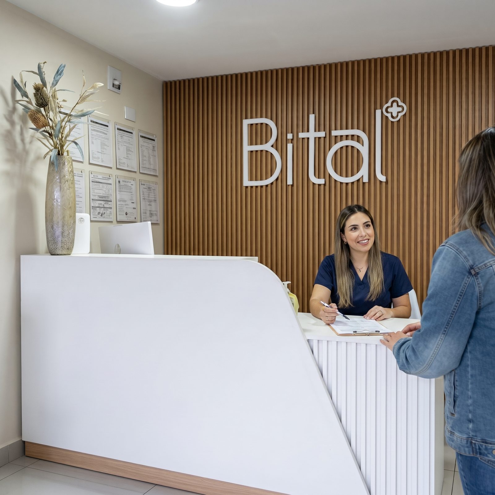 Recepcionista de Clínica Bital atendiendo a una paciente en la recepción, Mérida